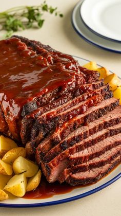 a plate topped with meat and potatoes covered in barbecue sauce next to another plate full of food