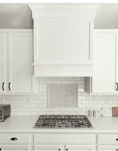 a kitchen with white cabinets and marble backsplash, an oven and toaster