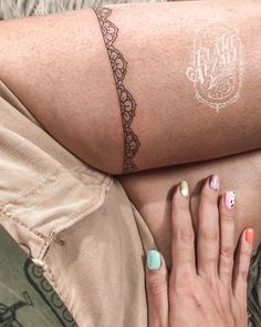 a woman's leg with a tattoo on it and her hand resting on the ground