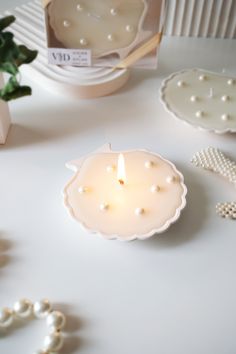 a white candle sitting on top of a table next to pearls