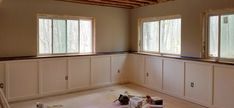 an empty room with several windows and some paint cans on the floor in front of them