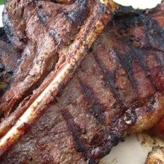 two pieces of steak sitting on top of a white plate