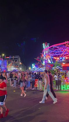 people are walking around an amusement park at night