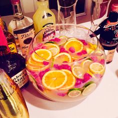 a bowl filled with lemons, raspberries and orange slices next to liquor bottles