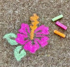 some crayons are laying on the ground next to a drawing of a flower