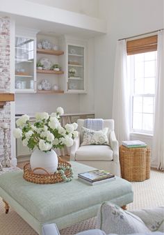 a living room filled with furniture and flowers in a vase on top of a coffee table