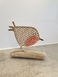 a small wooden bird sitting on top of a piece of wood