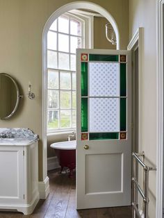 an open door leading to a bathroom with a tub and sink in it's center