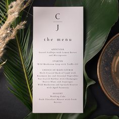 a menu card sitting on top of a table next to a plate and some plants