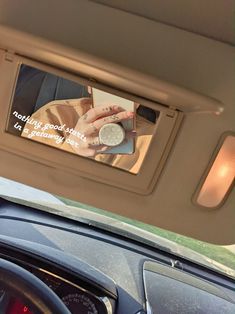 the rear view mirror is reflecting someone's hand holding a coin