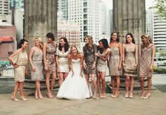 a group of women standing next to each other in front of some tall buildings and trees