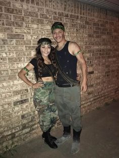 a man and woman standing next to each other in front of a brick wall at night