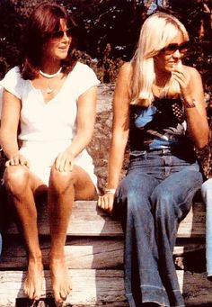 two women sitting on a wooden bench next to each other