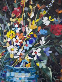 a vase filled with lots of colorful flowers on top of a tiled floor next to a wall