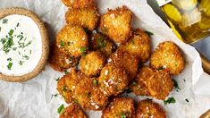 some fried food is on a white paper and next to a jar of ranch dressing