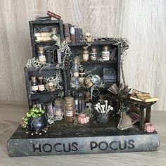 a book shelf filled with bottles and other items on top of a wooden table next to a wall