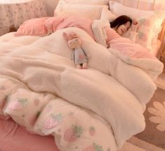 a woman laying in bed with a stuffed animal on top of the comforter and pillows