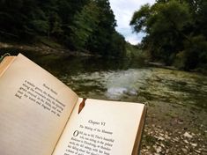 an open book sitting on top of a wooden table next to a body of water