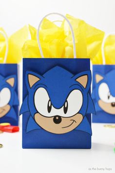 sonic the hedgehog party favors are on display in blue paper bags with yellow tissue pom - poms