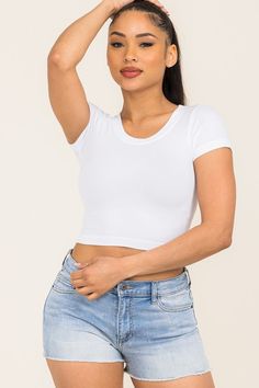 a woman in shorts and a white shirt posing for the camera with her hand on her head