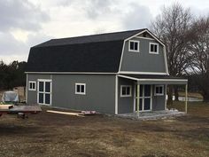 a large gray barn sitting in the middle of a field