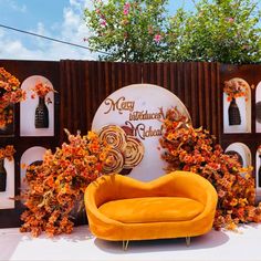 an orange couch sitting in front of a sign that says happy birthday and has flowers growing out of it