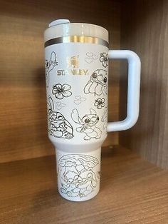 thermos travel mug with winnie the pooh characters on it is sitting on a wooden