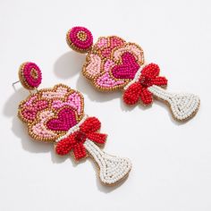 two pairs of beaded earrings with bows and hearts hanging from each earring on a white surface