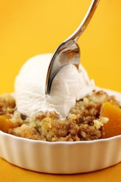 a scoop of ice cream is being lifted from a bowl of fruit cobbler crumbles