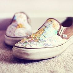 a pair of shoes that are sitting on the ground with maps painted on them and one has a white sole