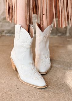 a woman wearing white cowboy boots with fringes