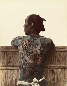 an old photo of a man with tattoos on his back