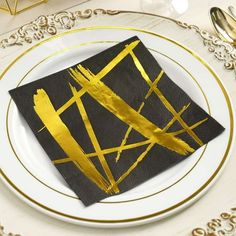 a white plate topped with a black napkin and gold foiled design on top of it