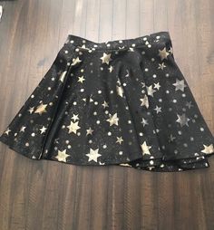 "Such a fun & flirty skirt featuring gold stars on a black background. Some of the gold stars are faded to a brass/bronze color. Unsure if this is the design or from washing. Excellent pre-owned condition, no holes or  Waist 13.5\" - 16\" Length 16\" Made in Korea SJL Apparel 90% polyester, 10% spandex Pull on with stretch waistband. Ships from a smoke free home" Little Black Lace Dress, Star Galaxy, Black Lace Dress, Beautiful Skirts, Gold Star, Bronze Color, Black Skirt, Gold Stars, Flared Sleeves