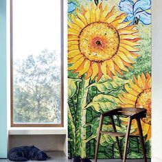 a cat is sleeping on the floor in front of a window with sunflowers painted on it