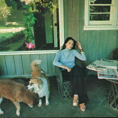 a woman sitting on a chair next to two dogs