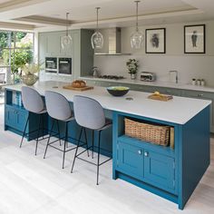 a large kitchen with blue cabinets and white counter tops, an island in the middle