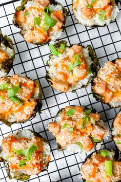 several sushi rolls on a cooling rack with sauce and green garnishes