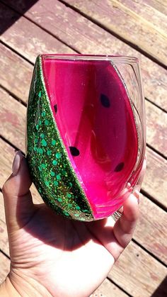 a hand holding up a wine glass with watermelon on the inside and green sprinkles