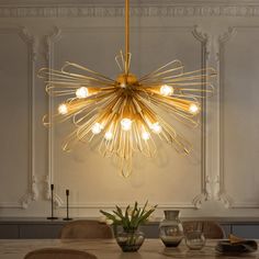 a chandelier hanging over a dining room table with chairs and vases on it