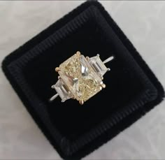 a fancy yellow diamond ring sitting on top of a black velvet box