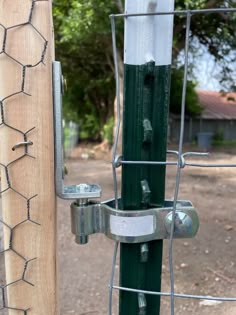 a close up of a metal fence with a wooden pole in the background