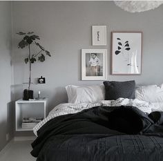 a black and white bedroom with pictures on the wall, bedding, and pillows