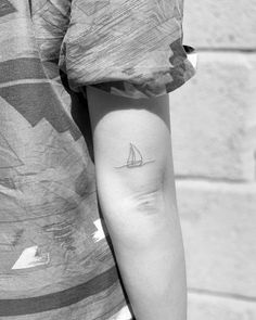 a person with a small sailboat tattoo on their left arm and the other arm