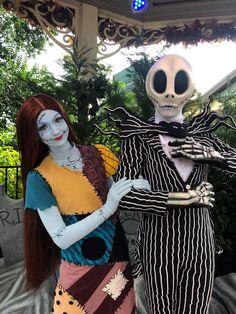 two people dressed up as jack and sally from the addams movie, one is holding a doll