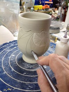 a person is working on a pottery vase