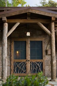 a wooden building with two doors and some plants in front of the entrance to it