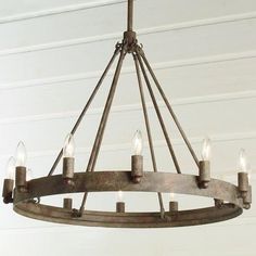 a chandelier with six candles hanging from it's center ring, on a white wall