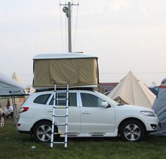 a white suv parked next to a tent with ladders on the roof and tents in the background