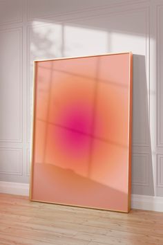 an orange and pink abstract painting sitting on top of a hard wood floor next to a white wall